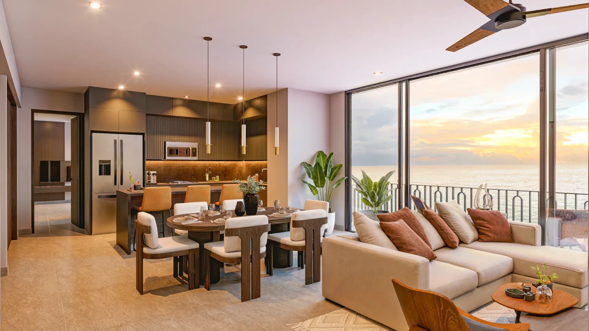 Spacious penthouse main living area at Amapas 314 featuring an open-concept gourmet kitchen, dining table, beige L-shaped sectional sofa, modern finishes, and wall-to-wall sliding glass doors with unobstructed ocean views at sunset