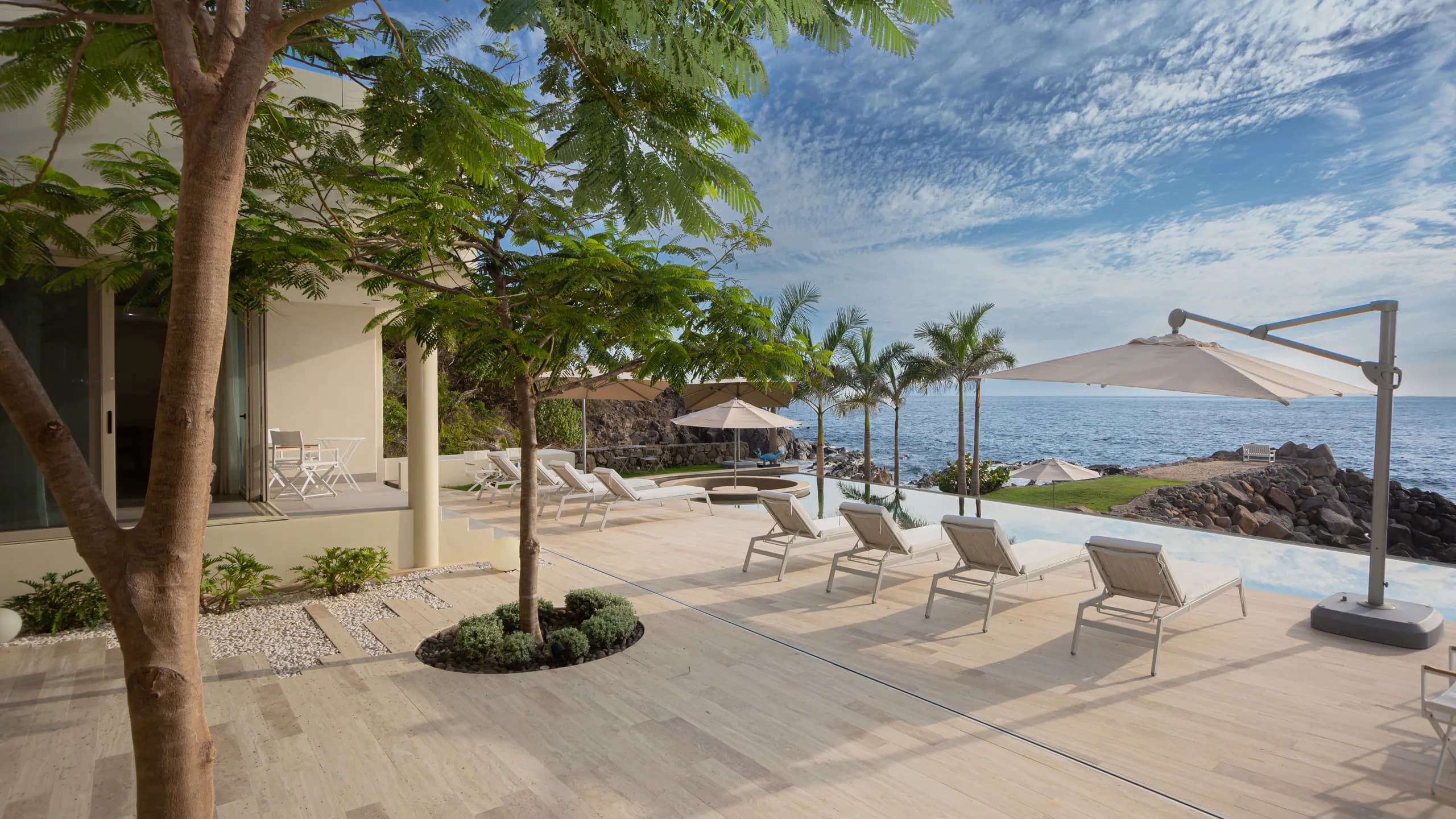 Expansive outdoor living areas seamlessly connected to the infinity pool and the Pacific shoreline beyond.