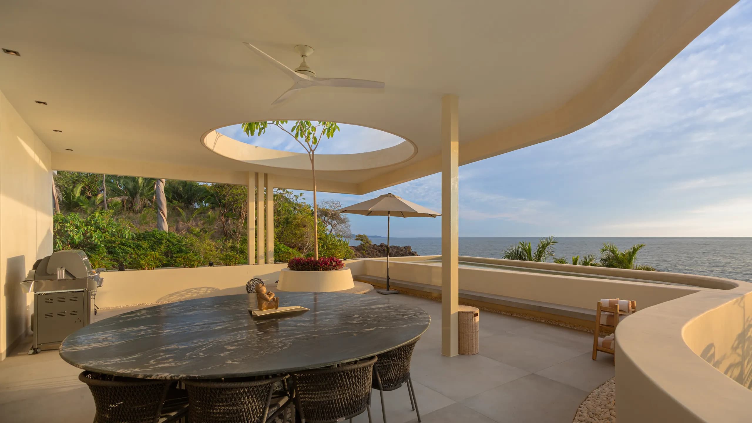 Private outdoor dining terrace overlooking the Pacific, framed by sculptural architectural lines and open coastal views.