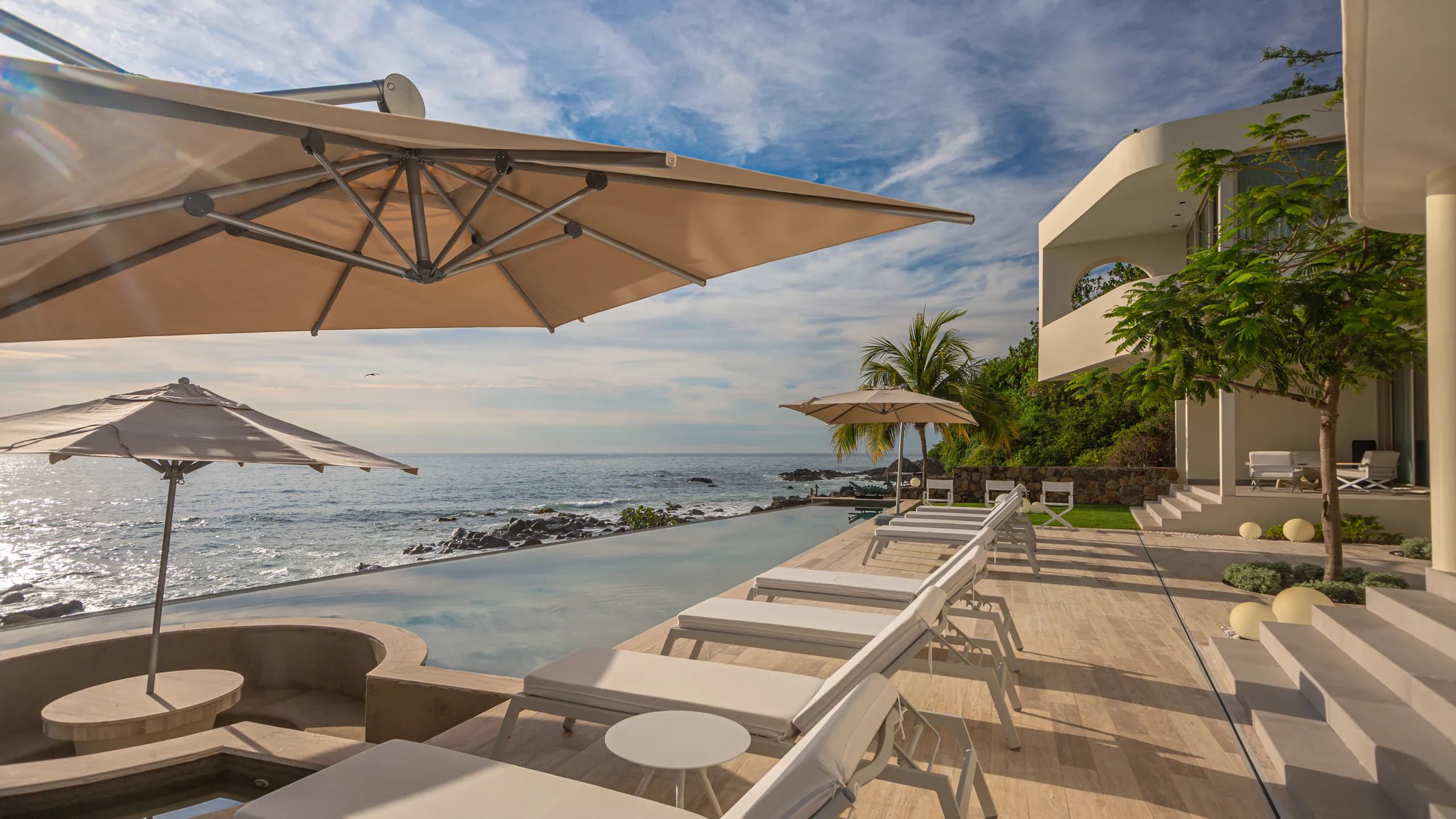 Private oceanfront lounge spaces positioned along the edge of the coastline, creating a refined indoor-outdoor experience.